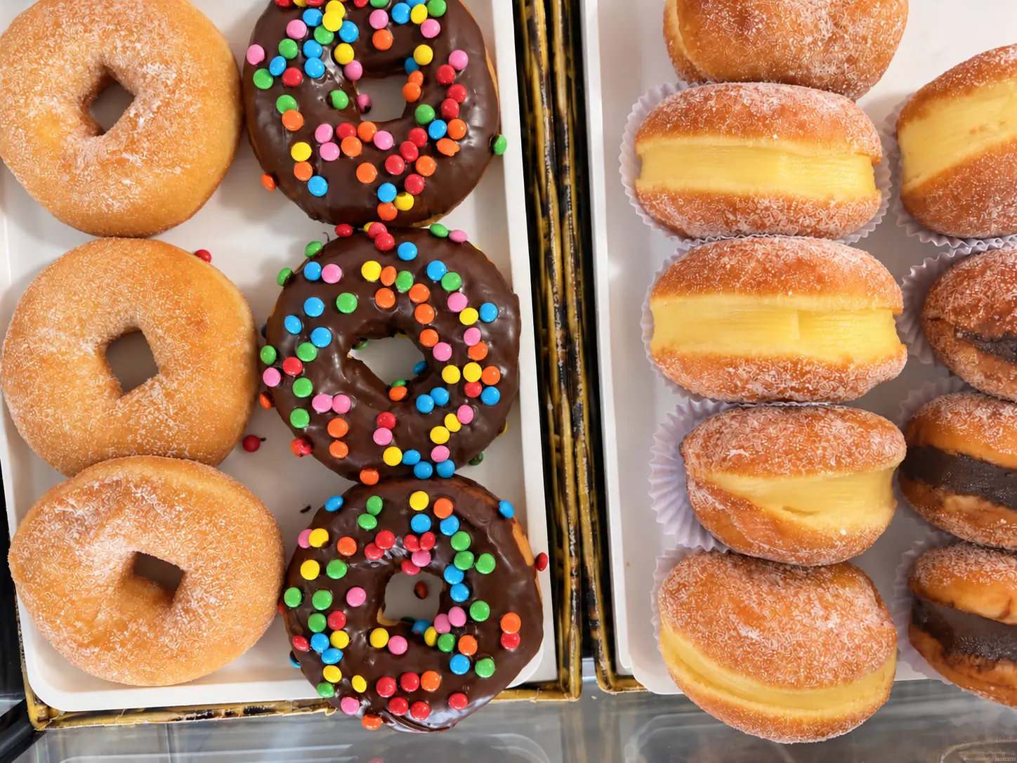 Bandejas de donuts cobertos de chocolate e sonhos recheados com creme