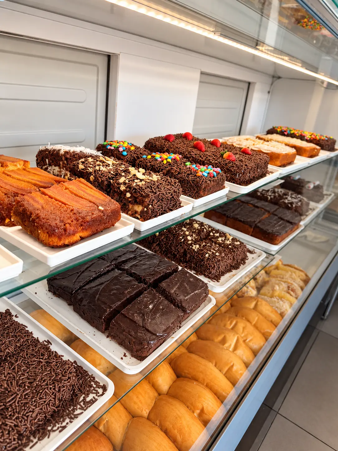 Vitrine de confeitaria com fatias de bolo, tortas e pães doces