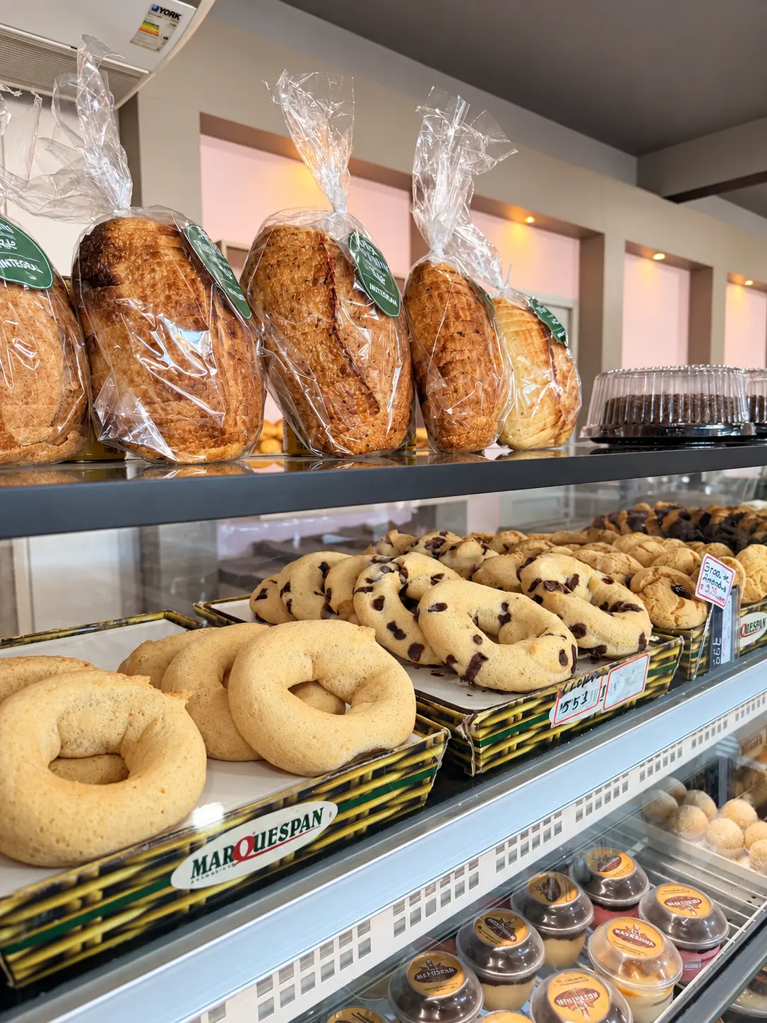 Balcão da padaria com pães embalados, biscoitos e potinhos de doce